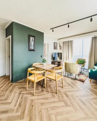 a dining room with a table and chairs and a green wall at Bethany Apartment ON PARK Century City in Cape Town