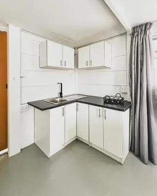 a small kitchen with white cabinets and a sink at Cedar Apartments on Century City in Cape Town