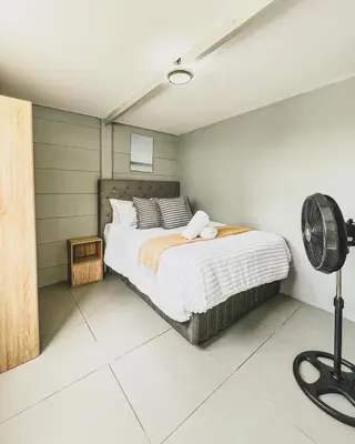 a bedroom with a bed and a fan at Cedar Apartments on Century City in Cape Town