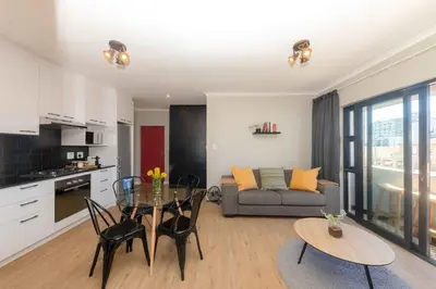 a kitchen and living room with a table and a couch at Cape on Porterfield in Cape Town