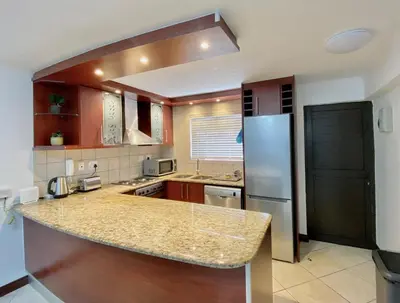 a kitchen with a granite counter top and a refrigerator at Peaceful 2-Bed Apartment in Boubergstrand in Cape Town