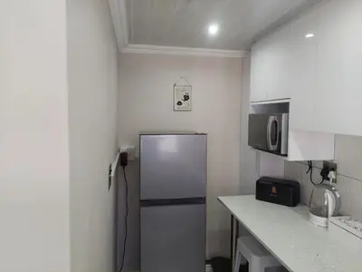 a small kitchen with a refrigerator and a microwave at Cosy Nook in Cape Town