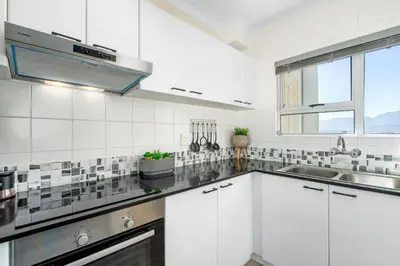 a white kitchen with a sink and a window at Odeon Towers 808 by Host Agents in Cape Town