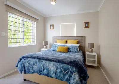 a bedroom with a bed with blue and yellow pillows at Whale - a - While in Hermanus