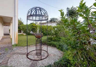 a bird cage in the middle of a garden at Whale - a - While in Hermanus