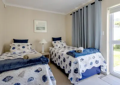 a bedroom with two beds and a window at Whale - a - While in Hermanus