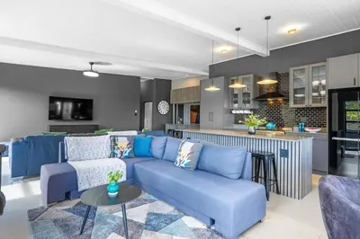 a living room with a blue couch and a kitchen at Red River Valley in Rooiels