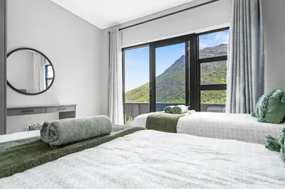 a bedroom with three beds and a large window at Red River Valley in Rooiels