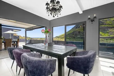 a dining room with a table and purple chairs at Red River Valley in Rooiels