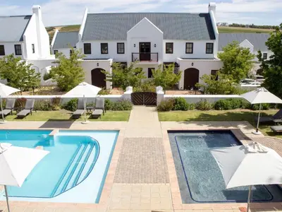 a house with a swimming pool and umbrellas at Winelands Golf Lodges 8 in Stellenbosch