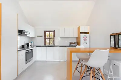 a white kitchen with a wooden table and white chairs at Winelands Golf Lodges 8 in Stellenbosch