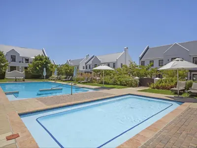 a large swimming pool in a yard with houses at Winelands Golf Lodges 13 in Stellenbosch