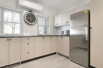 a kitchen with a refrigerator and a clock on the wall at Winelands Golf Lodges 22 in Stellenbosch