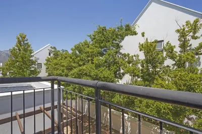 a balcony with a black railing and trees at Winelands Golf Lodges 22 in Stellenbosch