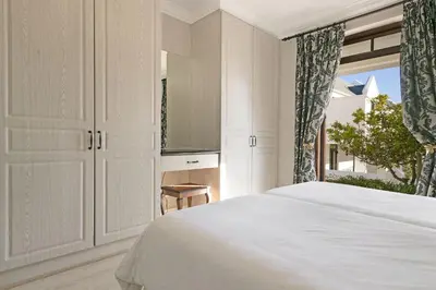 a white bedroom with a bed and a window at Winelands Golf Lodges 30 in Stellenbosch