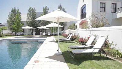 a group of chairs and an umbrella next to a pool at Winelands Golf Lodges 30 in Stellenbosch