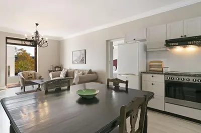 a kitchen and living room with a wooden table in a room at Winelands Golf Lodges 30 in Stellenbosch