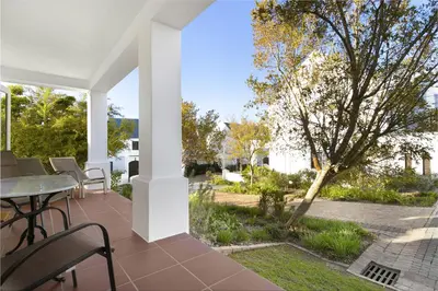 a patio with a table and chairs and a tree at Winelands Golf Lodges 37 in Stellenbosch