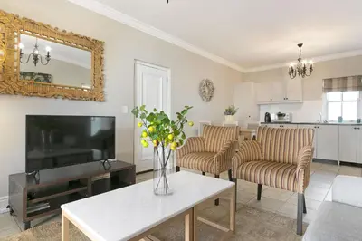 a living room with a tv and a table at Winelands Golf Lodges 37 in Stellenbosch