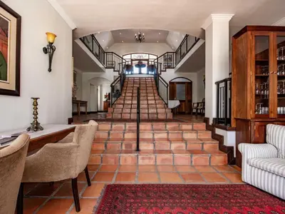 a hallway with a staircase with chairs and a couch at Winelands Golf Lodges 38 in Stellenbosch