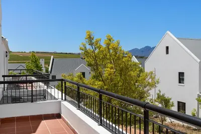 a balcony with black railings and trees and buildings at Winelands Golf Lodges 40 in Stellenbosch