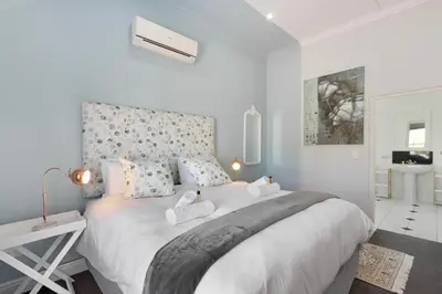 a white bedroom with a large white bed with pillows at Winelands Golf Lodges 40 in Stellenbosch