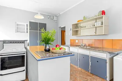 a kitchen with white appliances and a bowl of fruit on a counter at The Kleinmond Cottage in Kleinmond