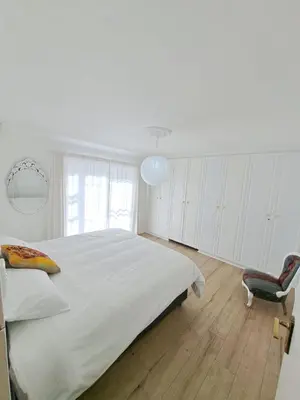 a white bedroom with a large bed and a chair at Stunning 3 Bedroom beach house in Bloubergstrand in Cape Town