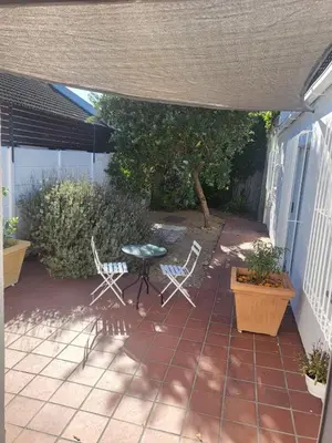 a patio with two chairs and a table and a table at Stunning 3 Bedroom beach house in Bloubergstrand in Cape Town