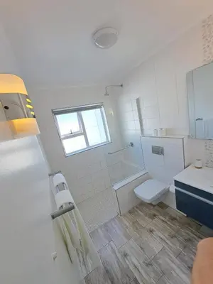 a white bathroom with a toilet and a sink at Stunning 3 Bedroom beach house in Bloubergstrand in Cape Town