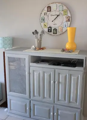 a white cabinet with a clock on the wall at Strandloper Apartments in Hermanus