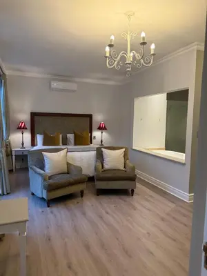 a bedroom with a bed and two chairs and a chandelier at Franschoek Lermitage Villa 33 Three Bedroom Lake View in Franschhoek
