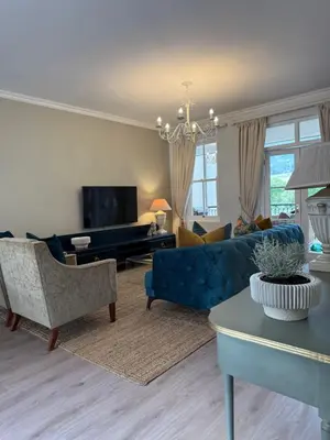 a living room with a blue couch and a tv at Franschoek Lermitage Villa 33 Three Bedroom Lake View in Franschhoek