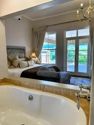 a master bedroom with a tub and a bed at Franschoek Lermitage Villa Two Bedroom Lake View in Franschhoek