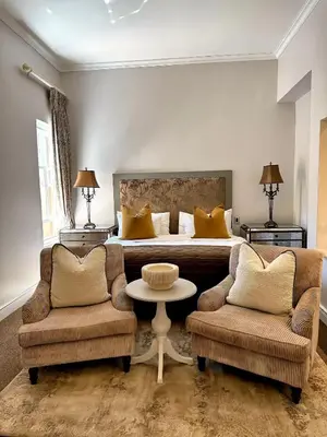 a bedroom with a bed and two chairs and a table at Franschoek Lermitage Villa Two Bedroom Lake View in Franschhoek