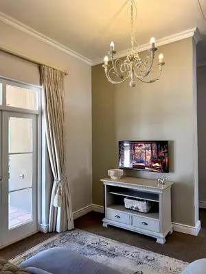 a living room with a television and a chandelier at Franschoek Lermitage Villa Two Bedroom Lake View in Franschhoek