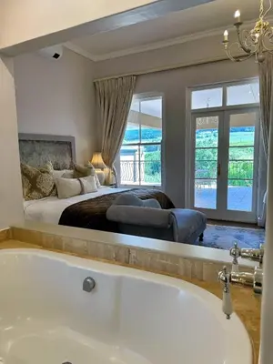a master bedroom with a tub and a bed at Franschoek Lermitage Villa Two Bedroom Lake View in Franschhoek