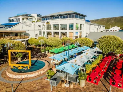 an aerial view of a resort with tables and umbrellas at Hermanus Waterfront Boho Studio Apartment, Whale Coast Hideaway in Hermanus