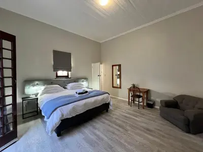 a bedroom with a bed and a chair and a couch at Avignon Guesthouse in Worcester