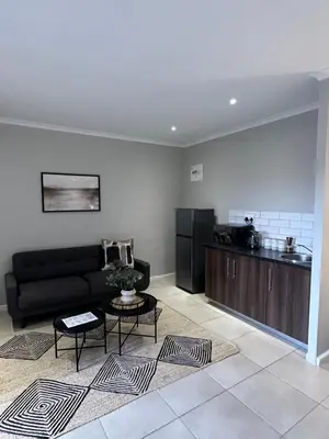 a living room with a black couch and a kitchen at Best Rest Somerset 3 in Somerset West
