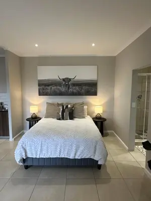 a bedroom with a bed with a bull painting on the wall at Best Rest Somerset 3 in Somerset West