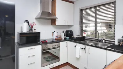 a kitchen with white cabinets and a sink and a stove at Happy Days in Paarl