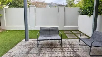 a patio with two chairs and a fence at Happy Days in Paarl