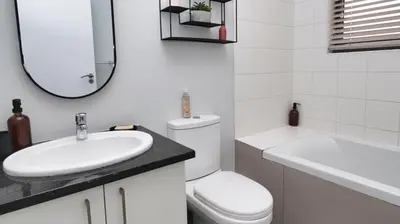 a bathroom with a sink and a toilet and a mirror at Happy Days in Paarl