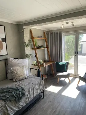 a bedroom with a bed and a chair and a window at Apartment in Gordon's Bay in Gordonʼs Bay