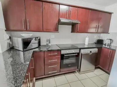 a kitchen with wooden cabinets and a stove top oven at Homely 3 Bedroom apartment in Villa Italia Century City in Cape Town