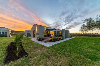 a house in a field with a sunset at LEO Sky Farm Cottages in Simondium