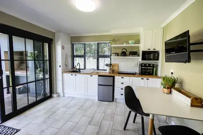 a kitchen with white cabinets and a table with chairs at 44 on Mountain Drive in Hermanus
