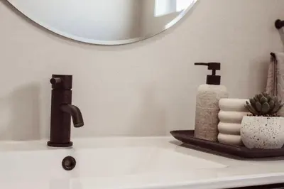 a bathroom sink with a soap dispenser and a mirror at Sage And Vine Studio in Worcester