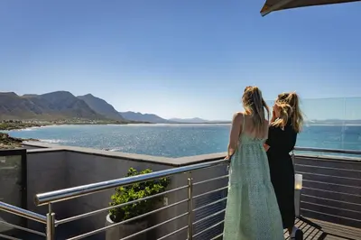 two women standing on a balcony looking at the water at Mountain-View Studio - Hermanus Waterfront Apartments in Hermanus